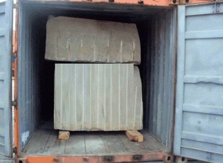 Large granite blocks loaded into a shipping container, showing how rough stone blocks are transported for export.